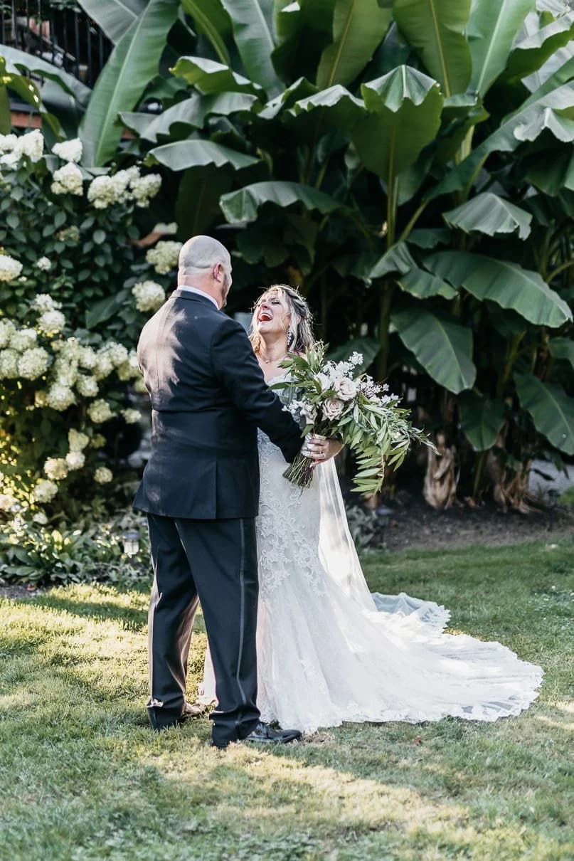 A couple embracing on the lawn among hydrangeas and broad garden foliage